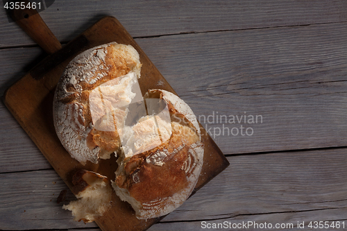 Image of Torned homemade bread loaf on old cutting board with a free space on the right