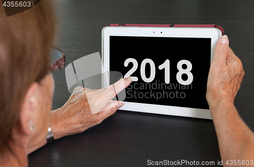 Image of Senior lady relaxing and her tablet - 2018