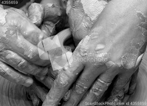 Image of Beginner and teacher in process of making clay bowl on pottery w