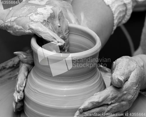Image of Two women in process of making clay vase on pottery wheel