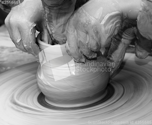 Image of Beginner and teacher in process of making clay bowl on pottery w