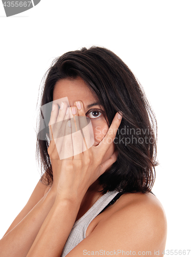 Image of Young woman looking through her fingers.