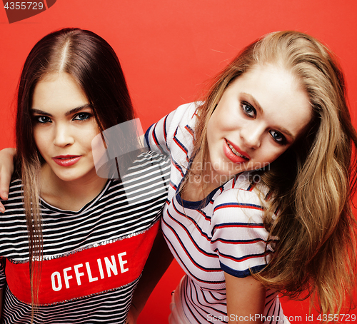 Image of two best friends teenage girls together having fun, posing emotional on red background, besties happy smiling, lifestyle people concept close up