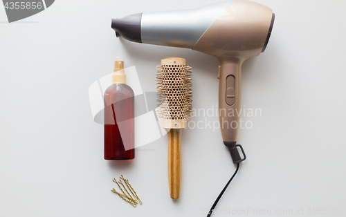 Image of hairdryer, brush, hot styling hair spray and pins