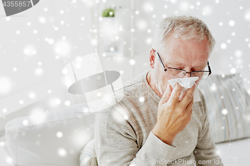 Image of sick senior man with paper wipe blowing his nose