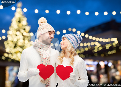 Image of couple with red hearts over christmas tree lights