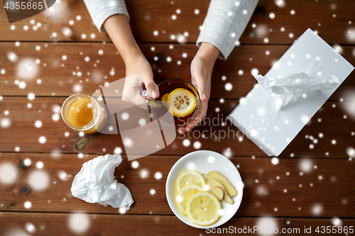 Image of ill woman drinking tea with lemon and ginger