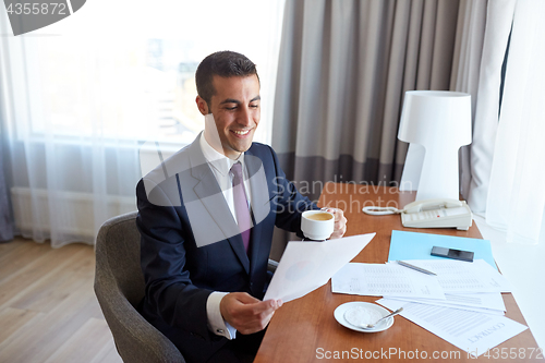 Image of businessman with papers drinking coffee at hotel