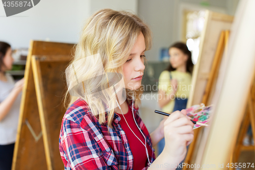 Image of student girl with easel painting at art school