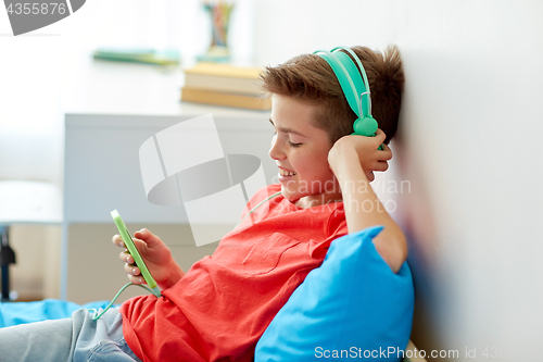 Image of happy boy with smartphone and headphones at home