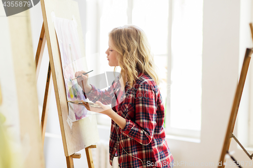 Image of student girl with easel painting at art school