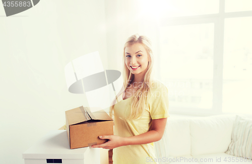 Image of smiling young woman with cardboard box at home