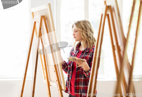 Image of student girl with easel painting at art school