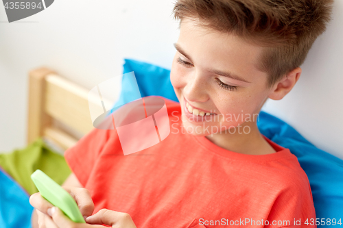 Image of close up of happy boy with smartphone at home