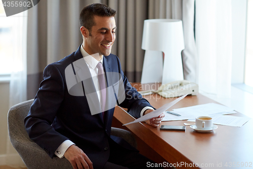 Image of businessman with papers working at hotel room