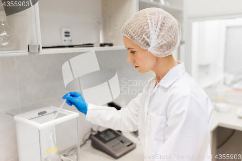 Image of woman with sulphuric acid and scale at laboratory