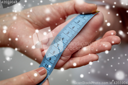 Image of close up of hands with tape measuring baby foot