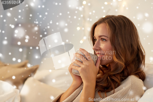 Image of happy woman with cup of coffee in bed at home