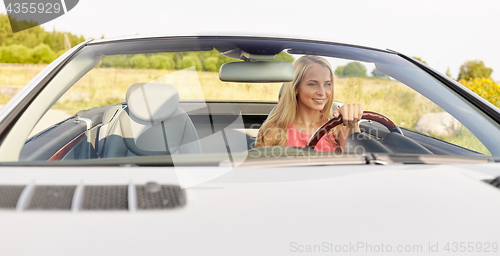 Image of happy young woman driving convertible car