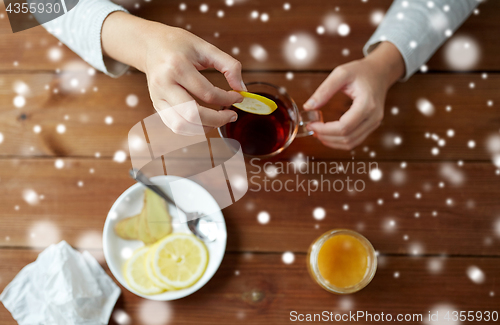 Image of close up of ill woman adding lemon to tea cup