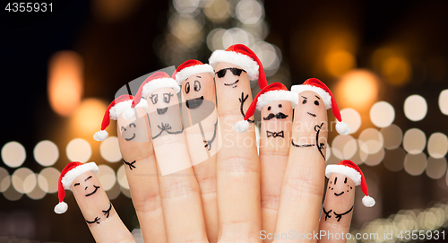 Image of close up of fingers in santa hats at christmas