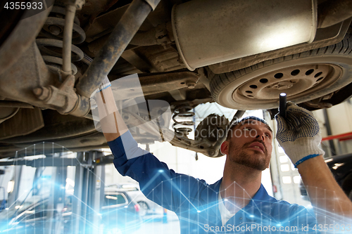 Image of mechanic man with flashlight repairing car at shop