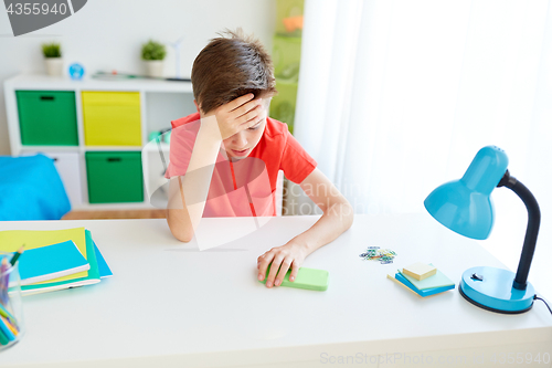 Image of tired student boy with smartphone at home