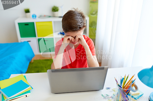 Image of tired student boy with laptop computer at home