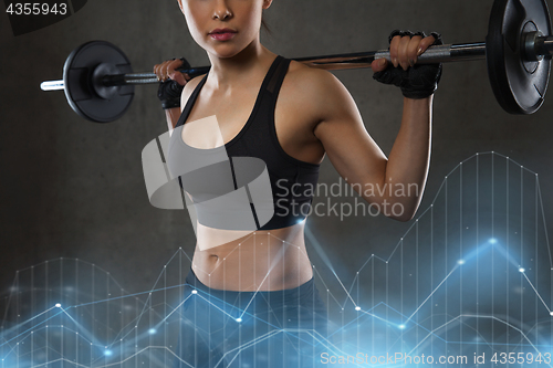 Image of young woman flexing muscles with barbell in gym