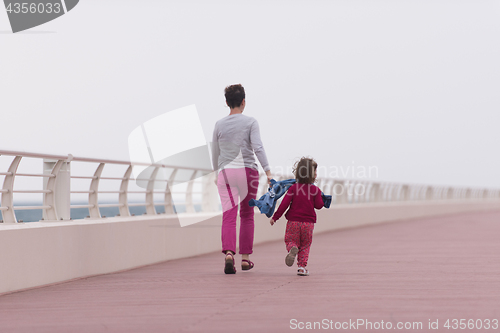 Image of mother and cute little girl on the promenade by the sea