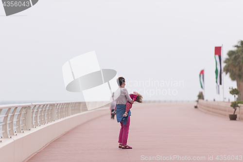 Image of mother and cute little girl on the promenade by the sea