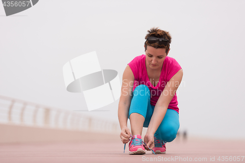 Image of Young woman tying shoelaces on sneakers