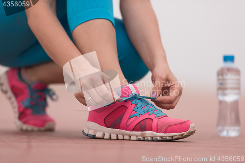 Image of Young woman tying shoelaces on sneakers