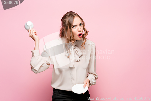 Image of The serious frustrated young beautiful business woman on pink background