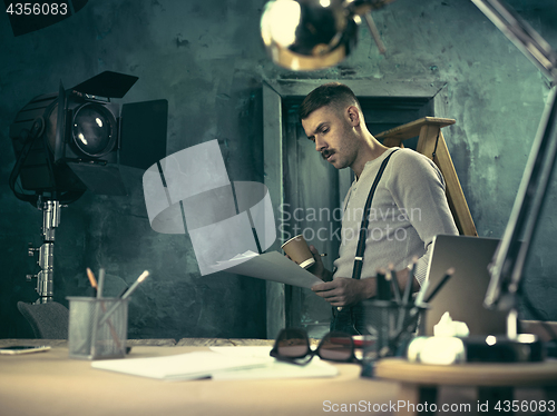 Image of Portrait of a bearded businessman who is checking details of his upcoming meeting in his notebook and typing.