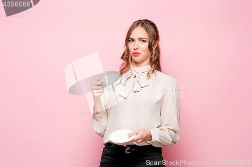 Image of The serious frustrated young beautiful business woman on pink background