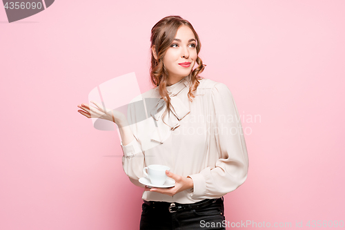 Image of The serious frustrated young beautiful business woman on pink background