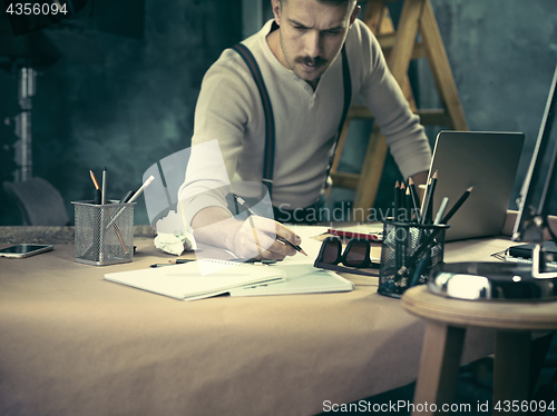 Image of Portrait of a bearded businessman who is checking details of his upcoming meeting in his notebook and typing.