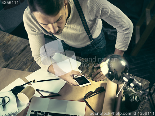 Image of Portrait of a bearded businessman who is working with his notebook at loft studio.