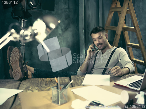 Image of Portrait of a bearded businessman who is working with his notebook at loft studio.