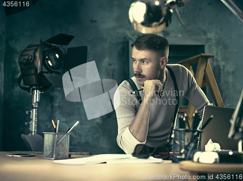 Image of Portrait of a bearded businessman who is checking details of his upcoming meeting in his notebook and typing.