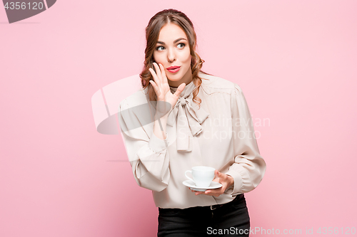 Image of The serious frustrated young beautiful business woman on pink background