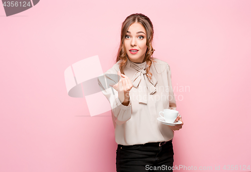 Image of The serious frustrated young beautiful business woman on pink background