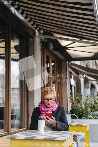 Image of Woman with drink and smartphone