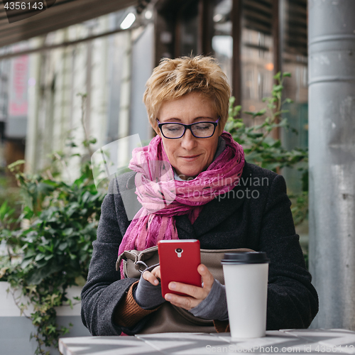 Image of Smiling woman with phone in cafe