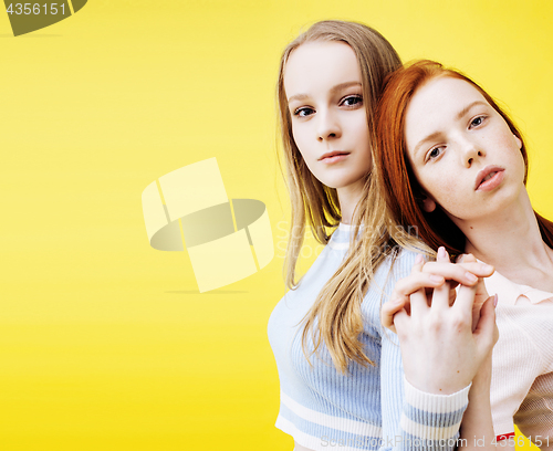 Image of lifestyle people concept: two pretty young school teenage girls having fun happy smiling on yellow background closeup