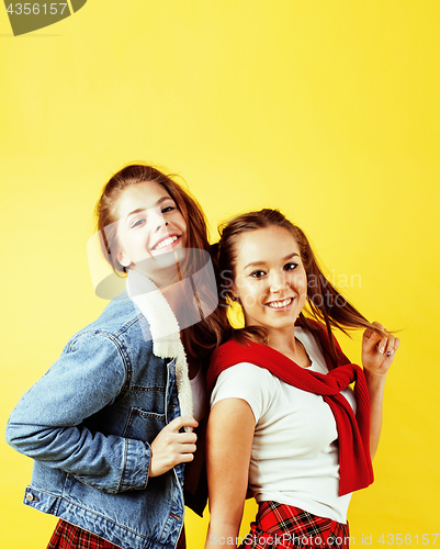 Image of lifestyle people concept: two pretty young school teenage girls having fun happy smiling on yellow background 