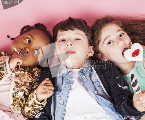 Image of lifestyle people concept: diverse nation children playing together, caucasian boy with african little girl holding candy happy smiling 