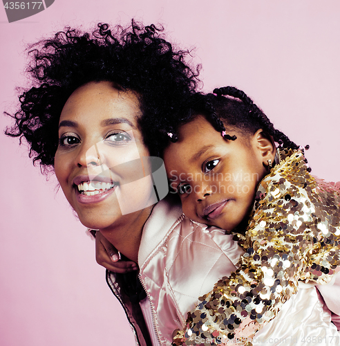 Image of young pretty african-american mother with little cute daughter hugging, happy smiling on pink background, lifestyle modern people concept closeup