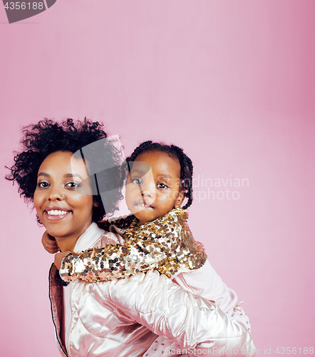 Image of young pretty african-american mother with little cute daughter hugging, happy smiling on pink background, lifestyle modern people concept closeup